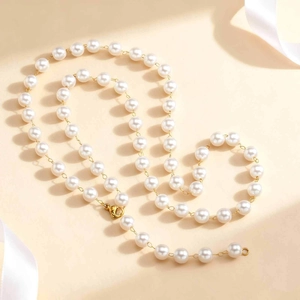 Detail of elegant gold clasp and round white pearls on a minimalist Y-shaped necklace