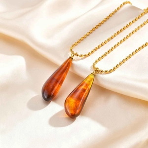 Detail of gold bead chain necklaces with vintage resin waterdrop pendants on silk