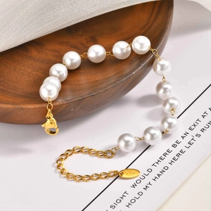 Elegant gold stainless steel pearl bracelet with K18 engraved tag on wooden background