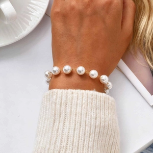 Elegant gold-plated stainless steel pearl bracelet worn with a white knit sweater