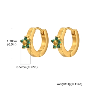 Dettaglio di orecchini a cerchio dorati con ciondoli a fiore in zircone verde
