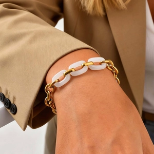 Gold stainless steel and white resin link chain bracelet on a woman's wrist