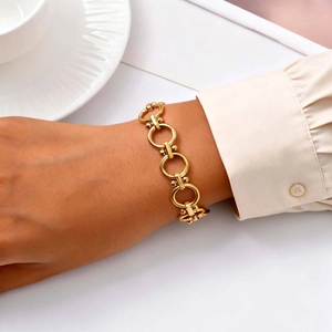 Detail showing an 18K gold-plated stainless steel square link bracelet on a female wrist