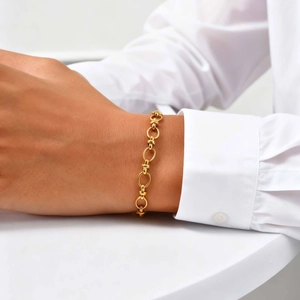 Detailed view of an 18K gold-plated oval link chain bracelet worn on a woman's wrist