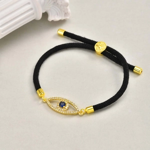 Detailed view of the copper Evil Eye charm with blue stone on black woven rope bracelet