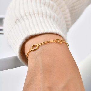 Women's 18K gold stainless steel chain bracelet with oval links on a white sweater background