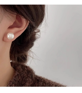 Primer plano de un pendiente de perla blanca clásica con brillo natural en la oreja