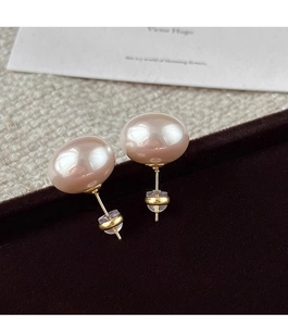 Primer plano de pendientes de perlas color champán en caja de terciopelo marrón