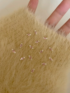 Macro detail of candy-shaped stud earrings with pink zircon on soft plush texture
