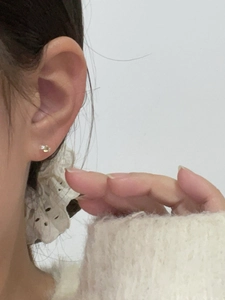 Close-up of minimalist mini candy stud earring with zircon on earlobe with soft sweater