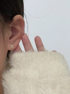 Close-up of minimalist mini candy stud earring with sparkling zircon on a model's ear