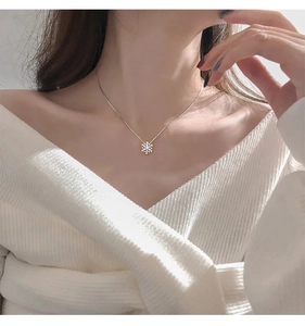Dettaglio della collana con fiocco di neve rotante argentato e cristalli sul collo di donna