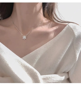 Dettaglio della collana a fiocco di neve rotante con zircone su maglione bianco
