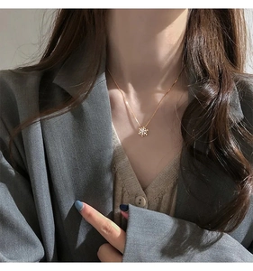 Dettaglio di una collana con ciondolo a fiocco di neve dorato e zirconi indossata da una modella
