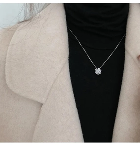 Dettaglio di una collana a fiocco di neve in argento con zircone su maglione nero