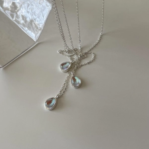 Close-up of teardrop necklaces with iridescent blue pendants on silver O-chains
