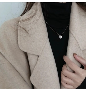 Primo piano di una collana con ciondolo a fiocco di neve argentato rotante con cristalli