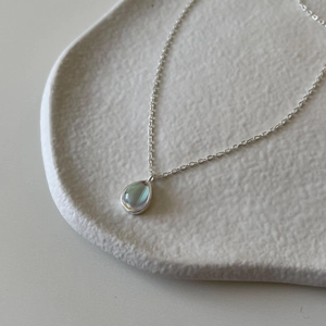 Detailed close-up of water drop shaped blue pendant on a silver metal chain