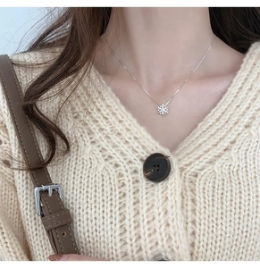 Collana con fiocco di neve rotante in argento indossata su maglione lavorato a maglia