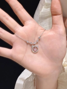 Detailed close-up of a silver cat-eared pendant with a pink star-shaped crystal held by hand