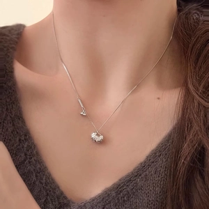 Silver hollow carved sphere pendant necklace on a model's neck with a cozy brown sweater