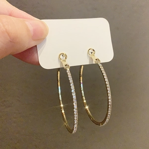 Große goldfarbene Creolen mit glitzernden Diamanten auf einer weißen Karte im Detail