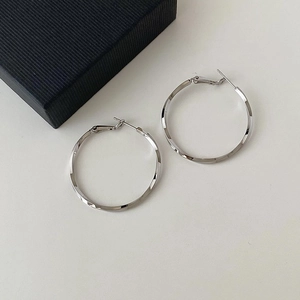Vista de detalle de pendientes de aro plateados trenzados con acabado metálico texturizado