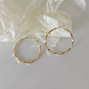 Primer plano de pendientes de aro dorados trenzados con textura detallada y brillo