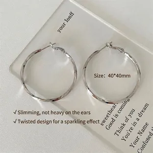 Detalle de pendientes de aro plateados trenzados con medidas de 40x40mm en placa