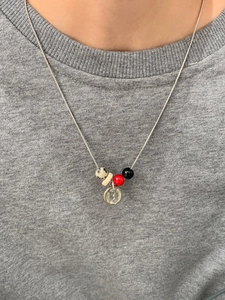 Detail van kralenketting met gespikkelde steenkraal en rood accent op slangenketting