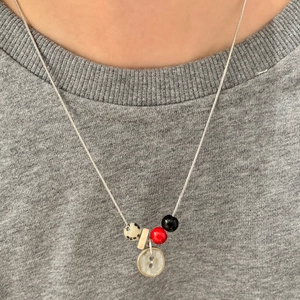 Handgemaakte kralen slangenketting met kleurrijke hangers op grijze t-shirt achtergrond