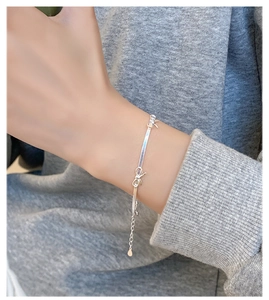 Primo piano di un bracciale a serpente minimalista in argento con fiocco al polso