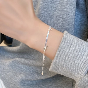 Bracciale a serpente in argento con fiocco su polso con maglione grigio in maglia