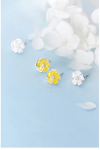 Detail of S925 silver flower stud earrings in white and yellow enamel with soft lighting