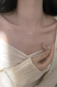 Nahaufnahme einer silbernen Schleifenkette am Hals für einen zarten, femininen Look