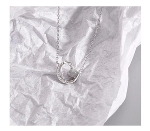 Macro detail of crescent moon pendant with micro-inlaid stones and grey moonstone gem