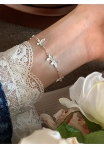 Detail of silver floral bracelet on wrist with delicate petals and matte finish
