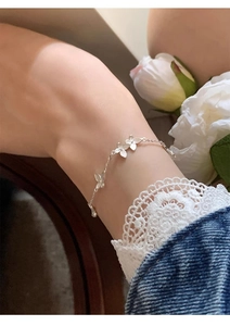 Silver butterfly charm bracelet worn on wrist with lace sleeve and white rose detail