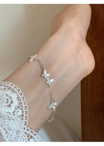 Close-up of elegant 925 silver butterfly anklet with detailed charms on woman's ankle