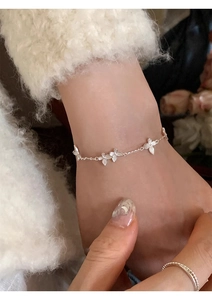 Close-up of delicate silver flower bracelet worn with a soft white knitted sweater