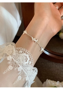 Silver butterfly bracelet on wrist with elegant lace details and dainty metallic charms