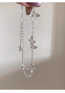 Detail of silver-plated butterfly bracelet with five textured charms held by fingers