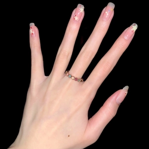 Rainbow gemstone ring with rose gold plating shown on hand against a black background