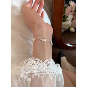 Elegant silver butterfly bracelet featuring delicate textured charms on a model's wrist