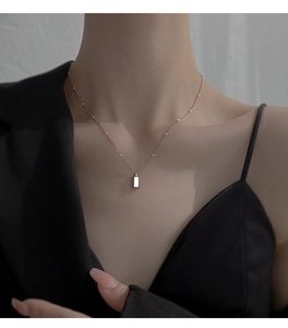 Close-up of minimalist silver bar necklace with bead chain on model's neckline