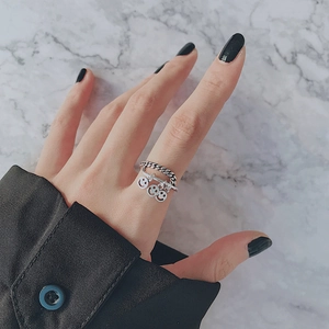 Detalle de un anillo punk plateado con tres colgantes de caritas sonrientes en el dedo