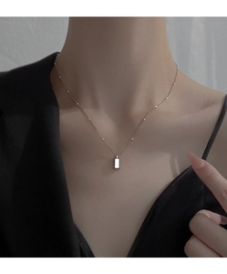 Detail shot of a silver minimalist rectangular pendant on a beaded chain worn by a model