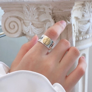 Detalle de anillo retro plateado con un emoji sonriente dorado de ojos de estrella