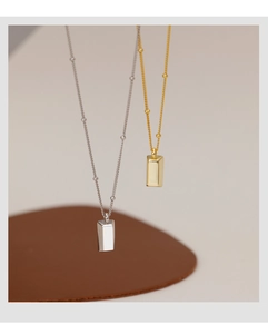 Close-up of minimalist gold and silver bar pendants on beaded chain necklaces