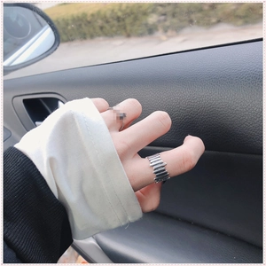 Detalle de anillo ancho plateado texturizado y banda trenzada en el dedo de mujer